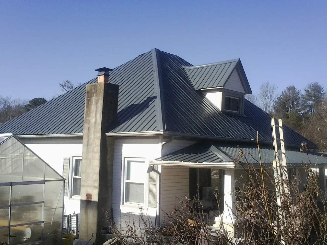 Dark blue standing seam metal roof on a white farmhouse with dormer — Slate & Tile Roof Repair by Roofing Brothers in South Easton