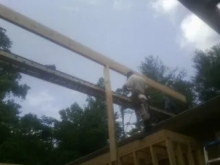 Carpenter setting a ridge beam over a new addition frame — Ice Dam Removal by Roofing Brothers in South Easton