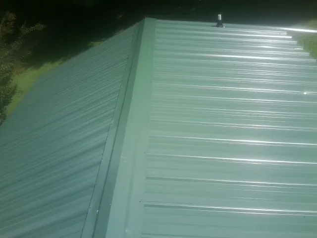 New green metal panels meeting at the ridge of a roof — Flat Roof Repair work by our crew in South Easton