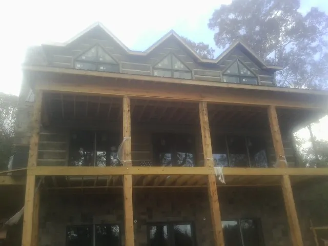Dormers and porch framing on a large log home under construction — Roof Coating work by our crew in South Easton