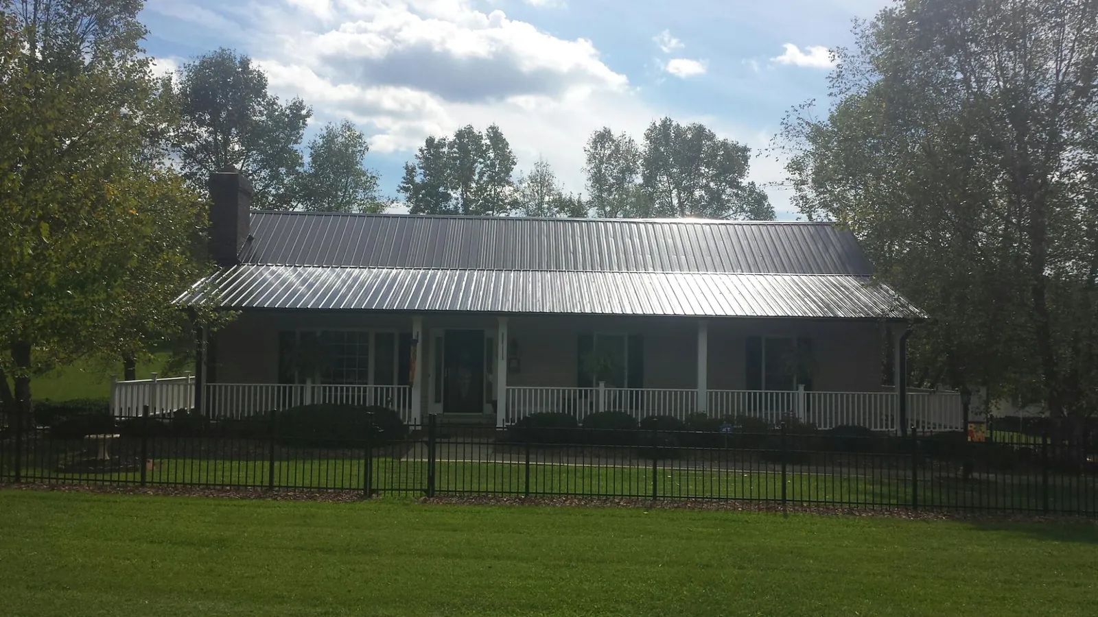 Gray metal roof on a brick ranch with a full width front porch — Gutter Guard Installation work by our crew in South Easton