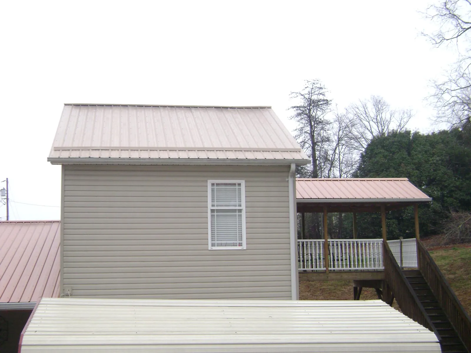 Tan metal roofs on a two story addition and attached porch, from a Roof Replacement job in South Easton