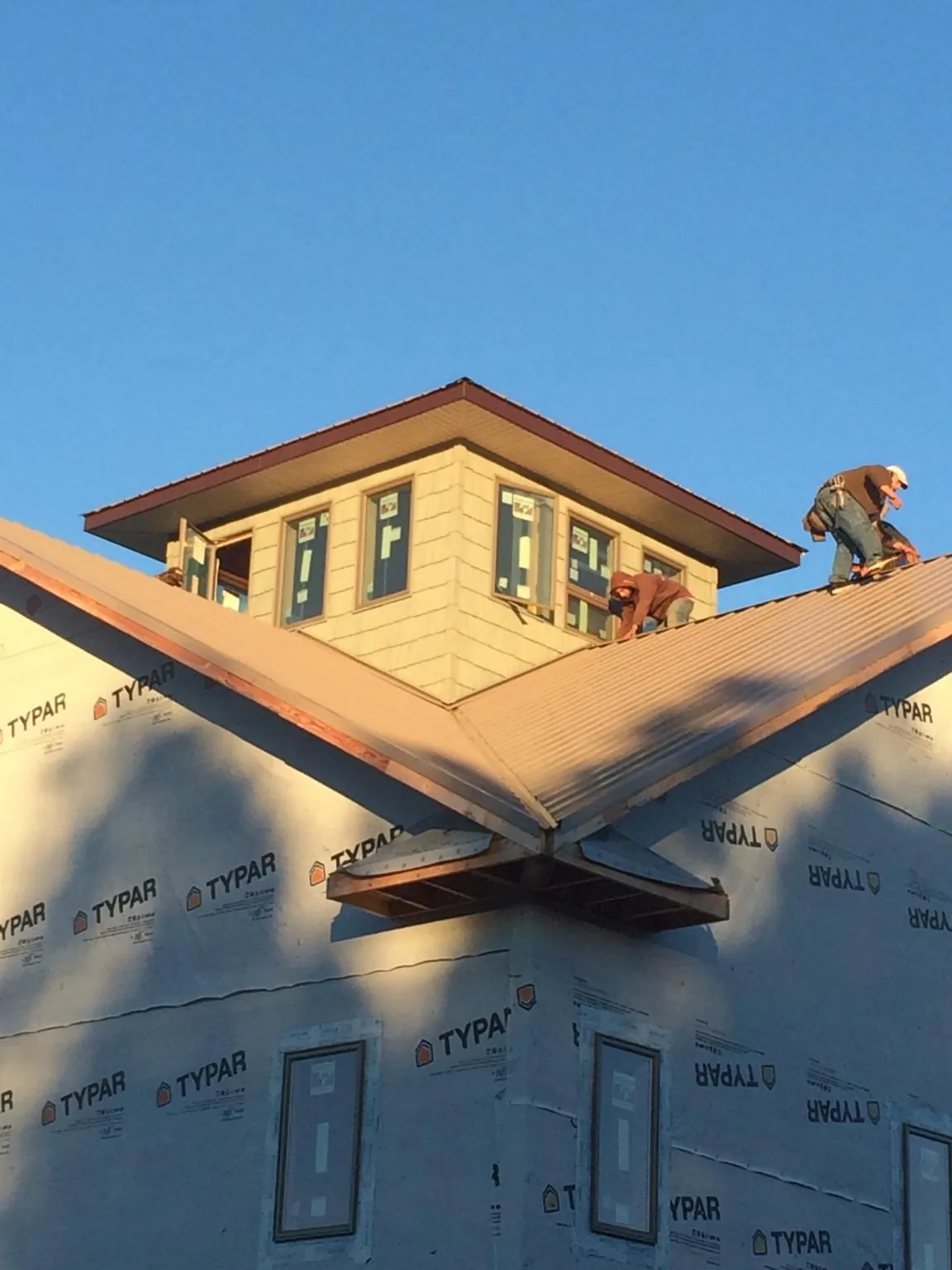 Roofers working around a rooftop cupola on a new metal roof at sunset — Roof Waterproofing in South Easton by Roofing Brothers
